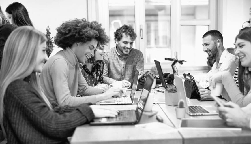 Young workers siting at a table with laptops.