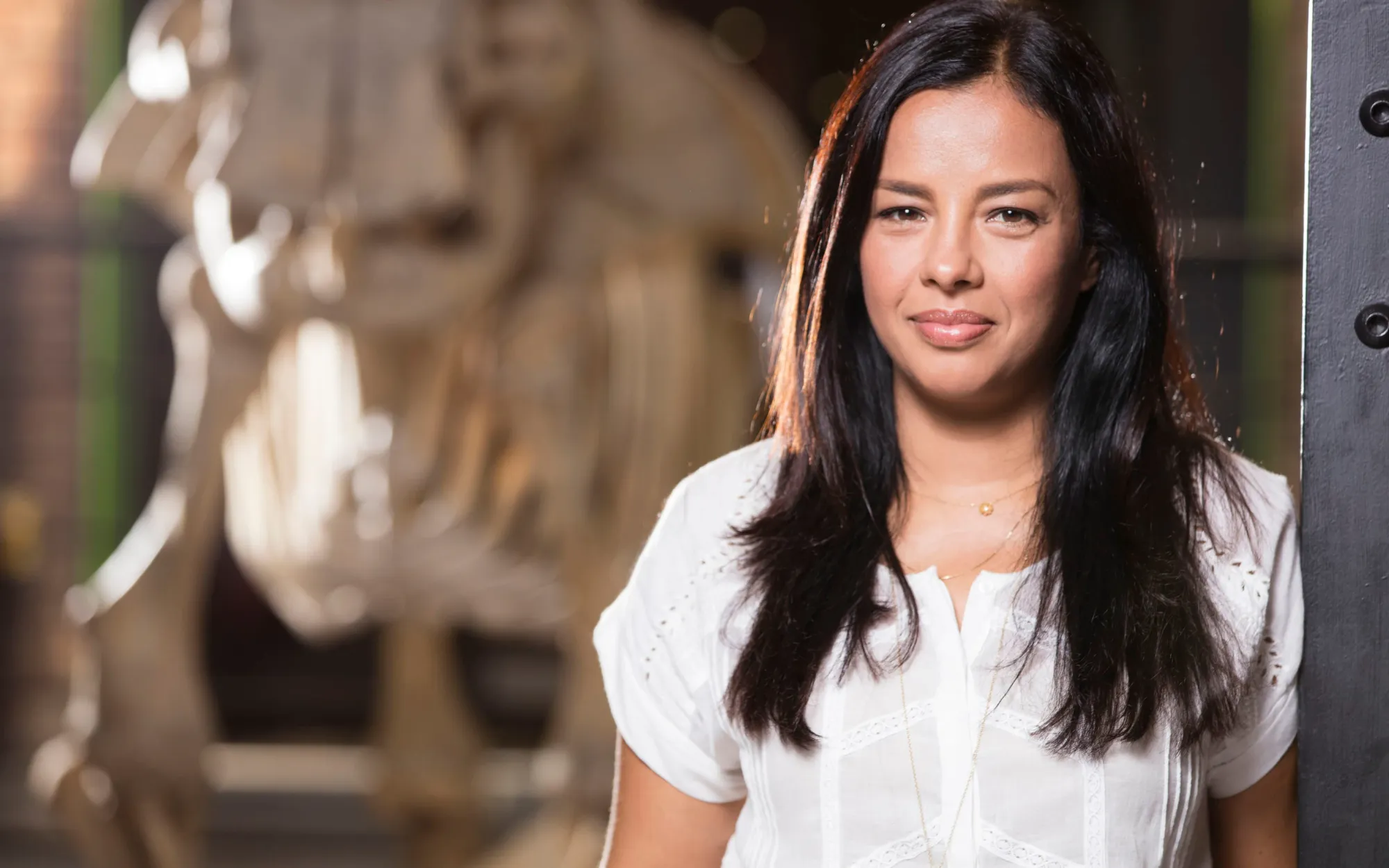 Liz Bonnin wearing a white shirt leaning against a wall.