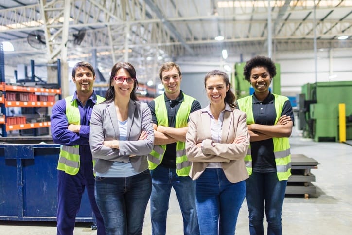 Young workers standing with their arms crossed while smiling.