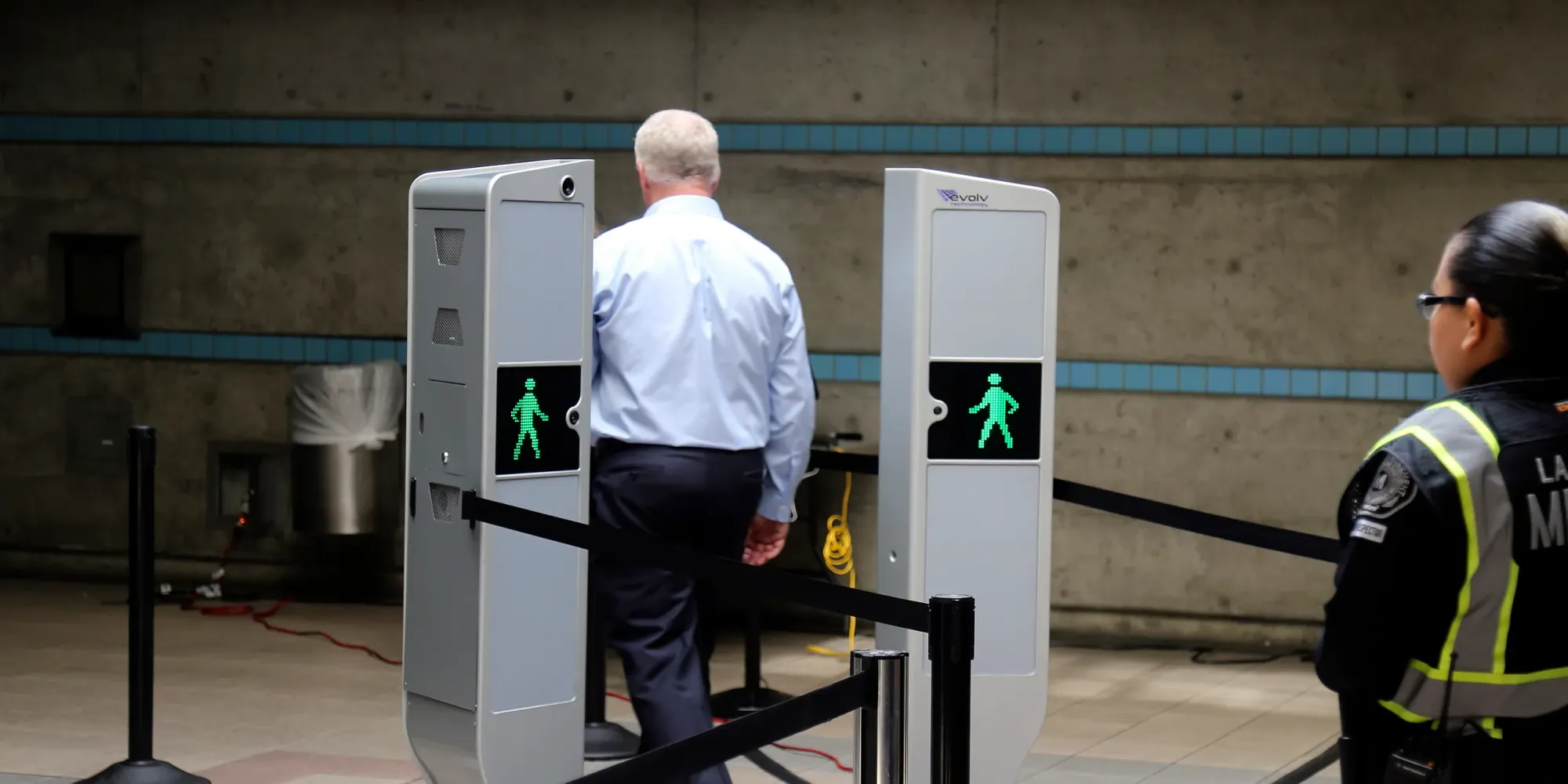 Man walking through a detection system. There are two panels on either side of him. 