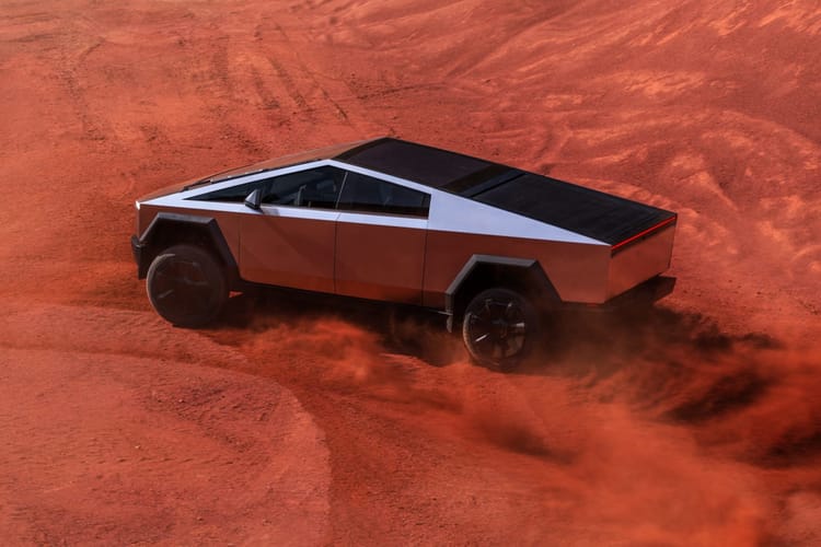 Tesla Cybertruck driving on red sand.