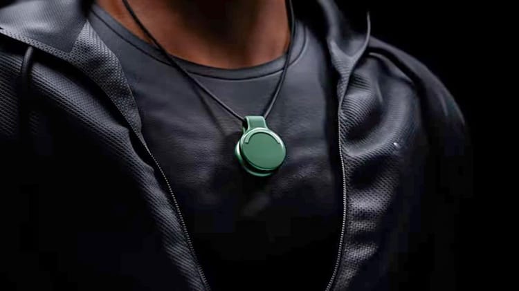 Man with black shirt and jacket wearing the Limitless AI Pendant in green.