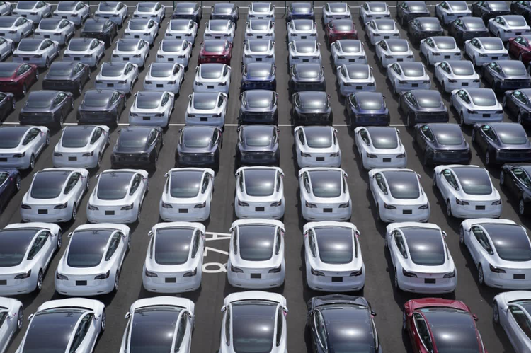 Aerial view of a parking lot filled with Tesla vehicles.